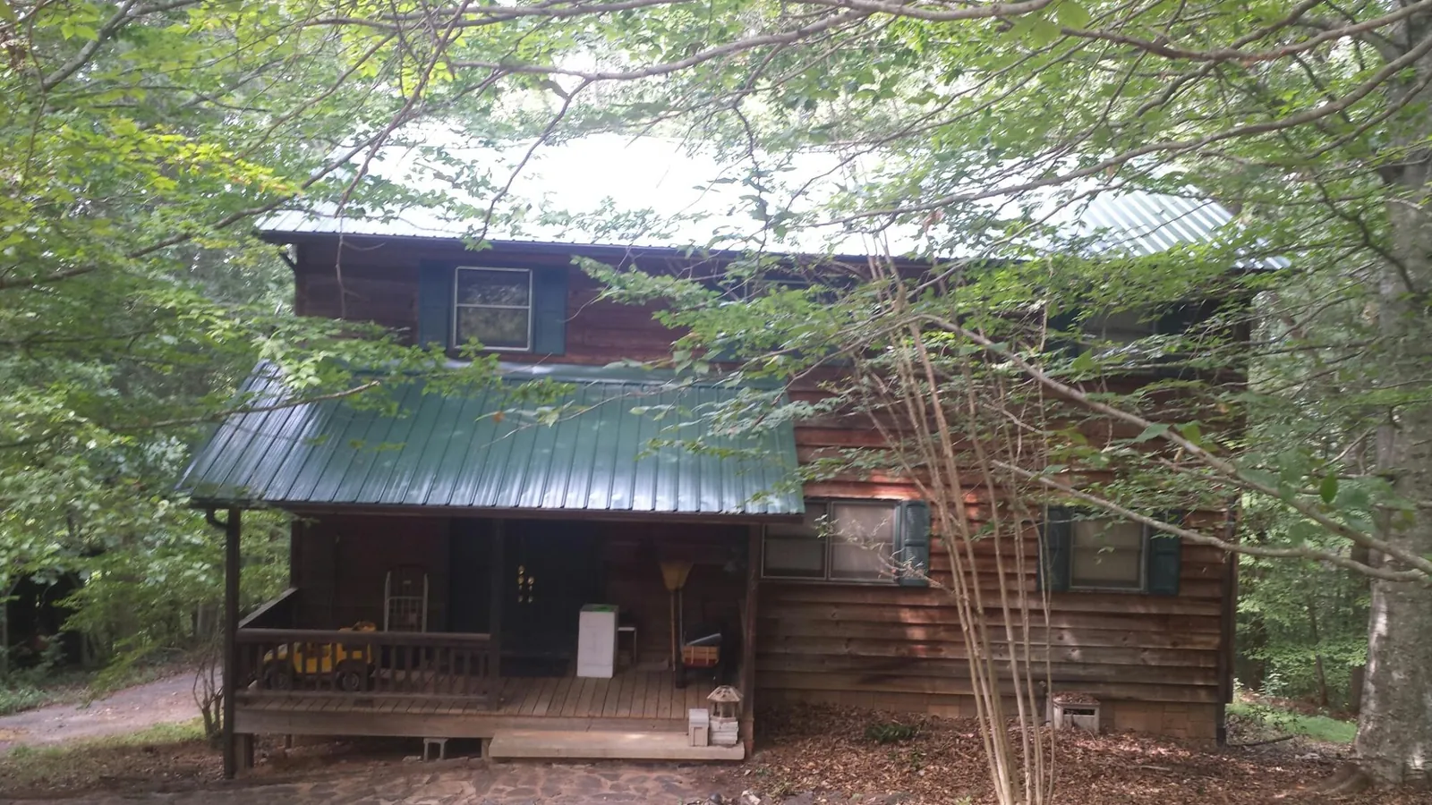 Green metal roof and covered porch on a log cabin in Walkerton