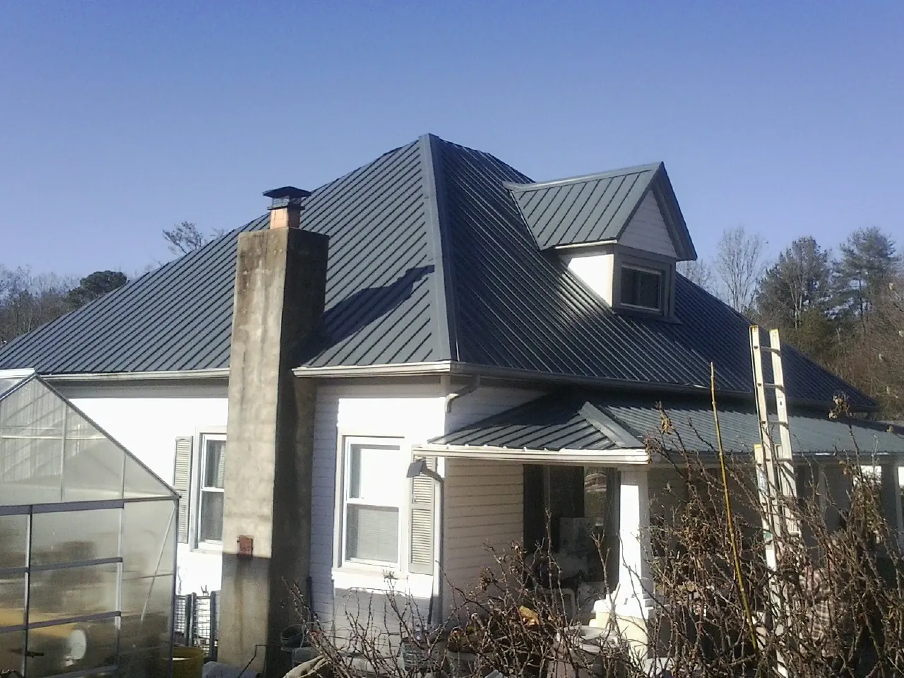Dark blue standing seam metal roof on a white farmhouse with dormer — Slate & Tile Roof Repair by Roofing Brothers in Walkerton