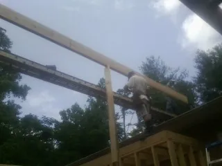 Carpenter setting a ridge beam over a new addition frame — Ice Dam Removal by Roofing Brothers in Walkerton