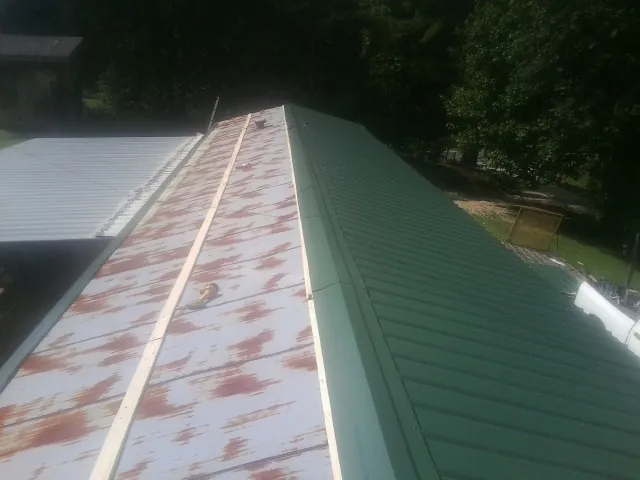 Old rusted panels beside newly installed green metal roofing — Wind Damage Roof Repair by Roofing Brothers in Walkerton